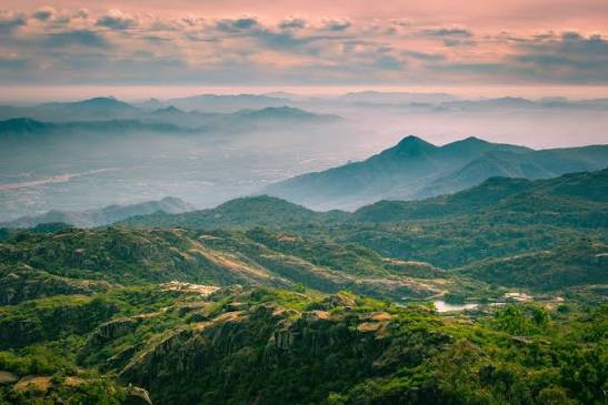 Misty green mountain ranges under pink sunrise